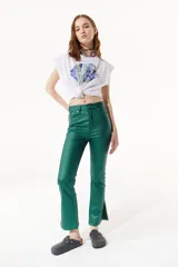 Pantalón jean verde esmeralda de tiro alto y corte acampanado con aberturas laterales en el ruedo.