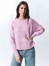 Mochila pequeña color rosa pálido con correas ajustables y asa superior. Tiene un bolsillo frontal con cierre y un parche con el logo de la marca en la parte inferior.