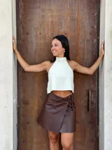 Minifalda tipo pareo confeccionada en cuero color chocolate, con diseño cruzado y cierre mediante tiritas laterales ajustables.