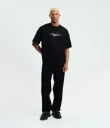 Remera boxy fit de algodón color negro, con cuello redondo y mangas cortas. Presenta un estampado de la cantante Amy Winehouse en blanco y negro con detalles en rojo, y la inscripción "Amy Winehouse Back to Black".