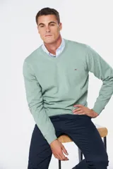 Suéter de tejido fino color azul marino, con cuello en V y manga larga. Presenta un pequeño logo bordado en el pecho.