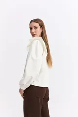 Camisa de color bordó con cuello mao y cierre frontal de botones. Presenta volados en los hombros que aportan volumen y un diseño sofisticado.