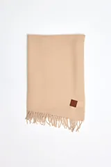 Pashmina de textura plisada en color beige, con flecos en el extremo inferior y un pequeño aplique de cuero sintético con logo grabado.