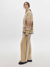 Pantalón de punto con textura tipo terciopelo, de corte ancho y holgado. Presenta cintura elástica con cordón de ajuste y detalle de pespuntes decorativos en los laterales.