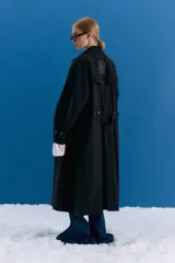 Trench midi color negro, confeccionado en mezcla de algodón y nylon con acabado repelente al agua. Presenta diseño con tajos laterales, bolsillos internos y etiqueta de marca en la espalda.