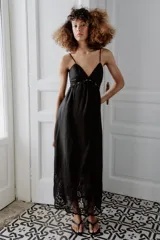 Vestido midi negro con escote en pico, tirantes finos y detalles de bordados y encaje en el escote y el bajo.