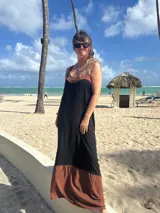 Vestido largo de fibrana, con corpiño negro ajustado y escote pronunciado en la espalda con tirantes anchos marrones. La falda es larga y voluminosa, con un ruedo ancho de tela marrón.