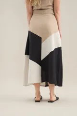 Falda larga de lino con diseño de cortes diagonales en bloques de color blanco, beige y tostado, de corte evasé y caída fluida.