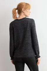 Remera de manga larga con cuello alto tipo media polera, confeccionada en tejido texturado de color beige melange, con puños con detalle de volados.