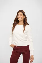 Cardigan de tejido de punto color blanco hueso, de manga larga y escote redondo, con cierre frontal de botones.