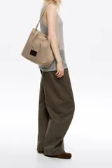 Bolso shopper de estructura blanda confeccionado en tejido de malla técnica negra. Cuenta con doble asa de hombro, cierre mediante cordón ajustable y etiqueta frontal con el logo de la marca Bimba y Lola.