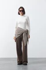 Pantalón de punto de corte relajado, con pierna recta y caída fluida. Presenta cintura elástica con cordón de ajuste y diseño liso en color marrón.