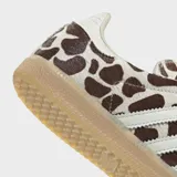 Championes Adidas Samba OG con diseño de estampado animal print tipo jirafa en tonos marrón y blanco. Presenta las icónicas tres bandas laterales en color blanco, cordones en celeste y suela de goma color caramelo.