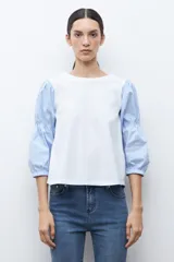 Remera de algodón con cuerpo liso en color blanco y mangas abullonadas de tela camisera con estampado de rayas finas en azul y blanco.