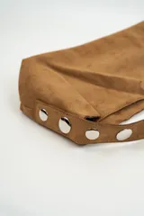 Bolso tipo baguette de gamuza color marrón, con correa ajustable mediante hebilla y cierre magnético central.
