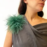 Broche decorativo compuesto por plumas de avestruz en color verde esmeralda, con forma circular y volumen esponjoso.