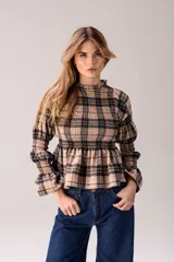 Blusa de manga larga con estampado a cuadros en tonos beige y negro, cuello alto con volados, diseño fruncido en el pecho y las mangas, y terminación acampanada en los puños y el bajo.