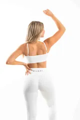 Conjunto deportivo compuesto por un top de escote cruzado y calzas de tiro alto con cintura en V. Ambas piezas son de color blanco y están confeccionadas en tela elástica técnica.