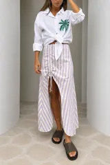 Falda larga de algodón con diseño de rayas en tonos lila y crudo, frunce regulable con cordones y abertura lateral en la parte frontal.