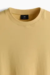 Remera de algodón de corte estándar, con cuello redondo y mangas cortas, en color mostaza.