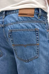 Jean de corte tapered, holgado en la cadera y levemente ajustado hacia los tobillos, con tiro medio y cierre frontal con botones.