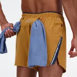 Short de running New Balance Impact Run 5 Inch, color ocre, con logo reflectivo y tecnología NB DRY de secado rápido.