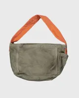 Bolso tipo tote o bandolera de lona color caqui con estampado frontal en azul marino que dice "COOLWAY PRESS". Posee una correa ancha de tela color naranja brillante y detalles en cuero marrón.