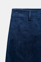 Falda midi de corte acampanado confeccionada en tejido con efecto ante color bordó. Presenta tiro medio, trabillas en la cintura y cierre frontal con cremallera y gancho metálico.