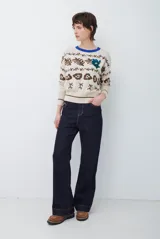 Buzo de tejido de punto en color beige con estampado de motivos florales y abstractos en tonos marrones. Presenta cuello redondo con borde en color azul vibrante, mangas largas y puños ajustados.