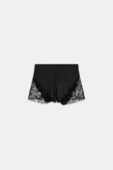 Shorts satinados de tiro medio y cintura elástica, color negro, con detalles de aplicación de encaje a tono en los laterales y cierre frontal de botones.