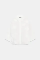 Camisa de tejido fluido color blanco, con cuello solapa, cierre frontal con botones y mangas amplias por debajo del codo. Presenta aplicaciones de flores en relieve a tono distribuidas por toda la prenda.