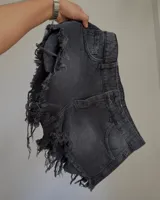 Short de denim color negro gastado, tiro alto, con detalles de roturas y flecos en los laterales y los bordes inferiores.