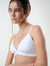 Bralette de algodón rib blanco, sin aro, con copas triangulares removibles y tirantes finos regulables. Presenta banda elástica inferior con sutil grabado.