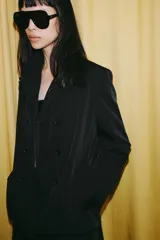 Blazer cruzado Zara de color negro, con cuello de solapa, manga larga y bolsillos laterales ocultos en la costura. Cuenta con cierre frontal de botones.