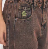 Pantalón de jean estilo barrel con efecto acid wash en tonos marrones y rosados, tiro medio y corte holgado en las piernas.
