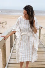 Túnica blanca con rayas verticales finas color dorado, corte holgado, mangas cortas amplias y lazo en la cintura.