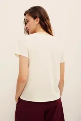 Remera blanca de algodón con cuello redondo, mangas cortas y estampa frontal de una guitarra rodeada de flores y la frase 'your own muse'.