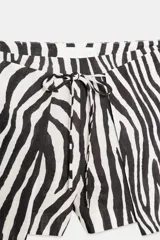 Shorts de tiro bajo con estampado de cebra en blanco y negro. Presenta cintura ajustable con cordones anudados al frente.