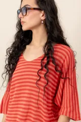 Sweater de tejido de punto a rayas horizontales en tonos beige y blanco, con escote en V y mangas cortas holgadas.