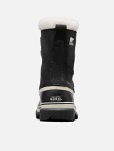 Bota de nieve Sorel modelo Caribou, con diseño impermeable de caña media. Presenta una parte superior de nubuck negro con costuras selladas, cordones frontales y una base de goma vulcanizada resistente. Incluye un forro interior de fieltro y detalle de pelo sintético en el borde superior.