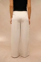 Pantalón de corte ancho, color crudo con delicadas rayas verticales negras, de tiro alto y diseño recto.