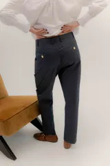 Pantalón sastrero de tiro medio, color gris oscuro con rayas verticales finas. Presenta pinzas delanteras, bolsillos delanteros con pin bordado y bolsillos traseros tipo vivo.