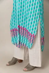 Túnica larga estampada en tonos turquesa, blanco y fucsia, con mangas cortas, calce holgado, tajos laterales y detalle de guarda en el ruedo.