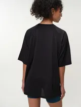Remera deportiva de color rosado con diseño oversized y mangas raglán cortas, confeccionada en tela dry fit. Cuenta con cuello redondo clásico y detalle de etiqueta en el lateral inferior.