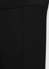 Leggings negros de corte entallado con estribos en la parte inferior, confeccionados en tejido elástico con costuras verticales decorativas.