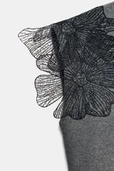 Top gris de cuello redondo y sin mangas, con detalle de flores negras de organza en los hombros.