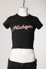 Remera baby tee blanca de morley, con ajuste al cuerpo, mangas cortas, cuello redondo y estampado con la inscripción 'Michigan' en estilo college.