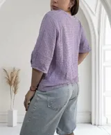 Blusa de manga corta color lila con cuello redondo y textura tejida en relieve con patrón de pequeños cuadros.