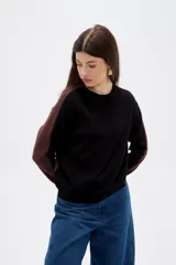 Sweater de viscosa con diseño color block, combinando frente negro con mangas y laterales en tono marrón. Presenta cuello redondo a la base y mangas largas.