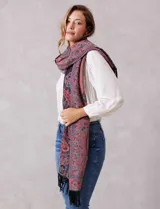 Bufandón rectangular de poliéster con estampado de arabescos en tonos rojos, azules y negros. Presenta terminaciones con flecos en los extremos.